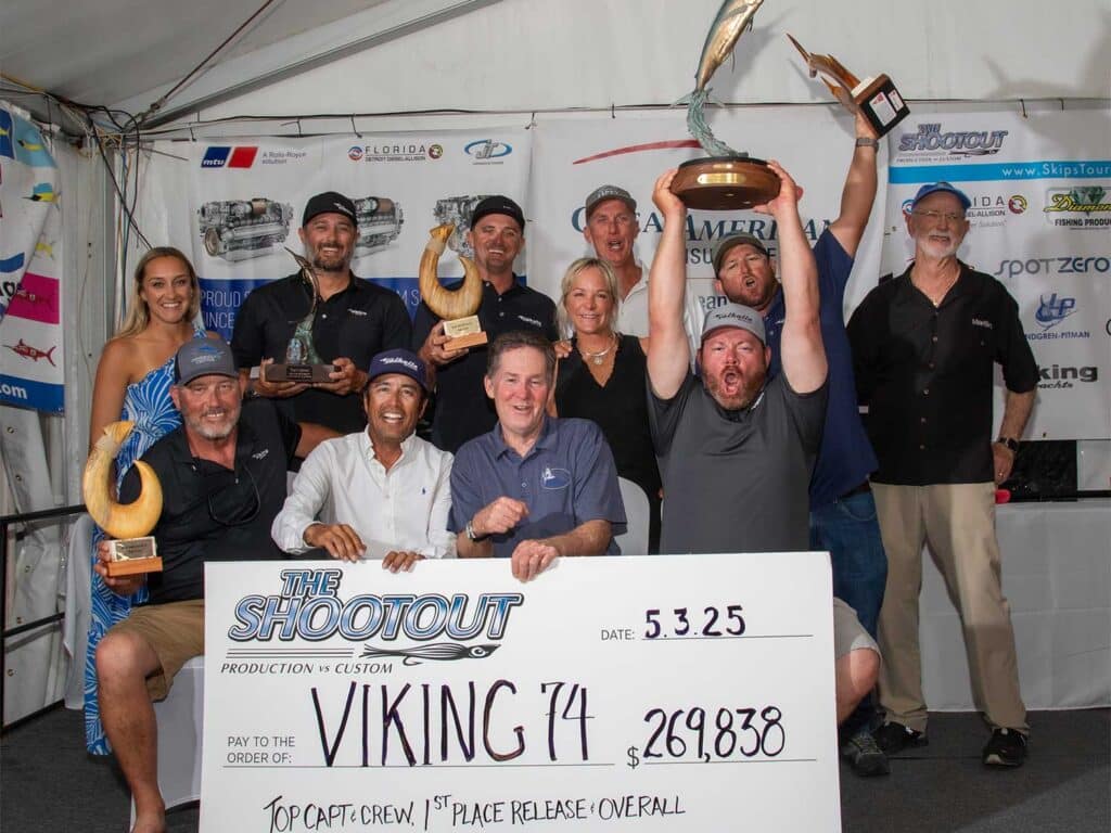 Team Viking 74 stands in celebration holding up trophies and an oversized check.