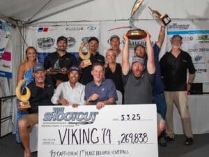 Team Viking 74 stands in celebration holding up trophies and an oversized check.