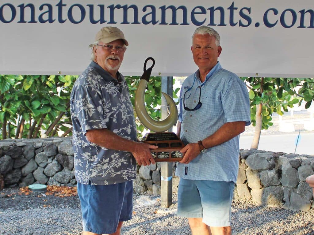 Capt. Jody Bright and David Ritchie shaking hands and holding a tournament trophy between them at the 2025 Lazy Marlin Hunt.