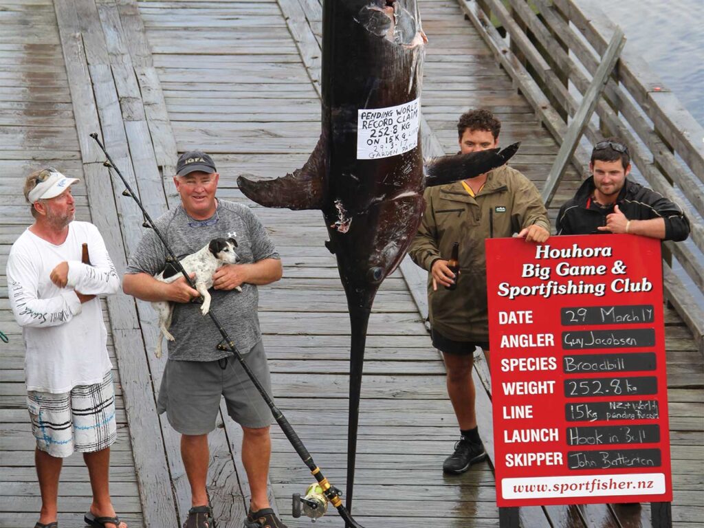 Four anglers stand around a broadbill being weighed at the docks.