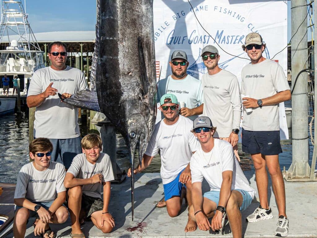 An angling team at standing next to a large blue marlin being weighed.