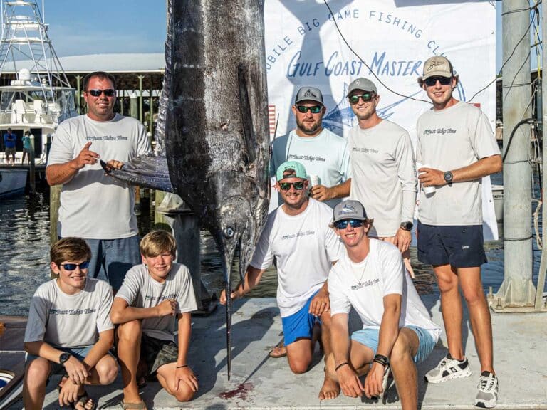 An angling team at standing next to a large blue marlin being weighed.