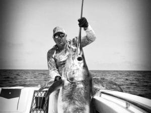 Black and white photo of Samuel Urbain with a swordfish