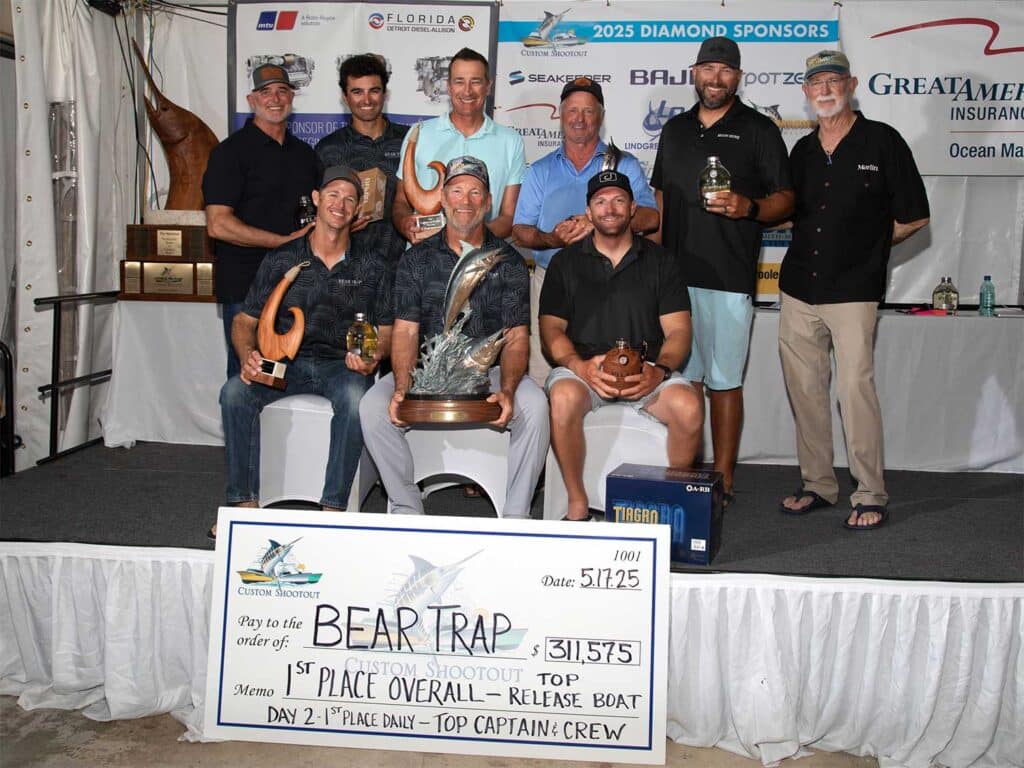A team of anglers pose in celebration while holding an over-sized check.