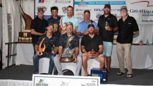 A team of anglers pose in celebration while holding an over-sized check.