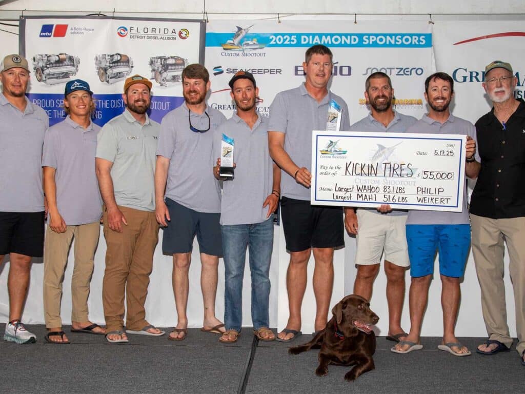 A team of anglers pose in celebration while holding an over-sized check.
