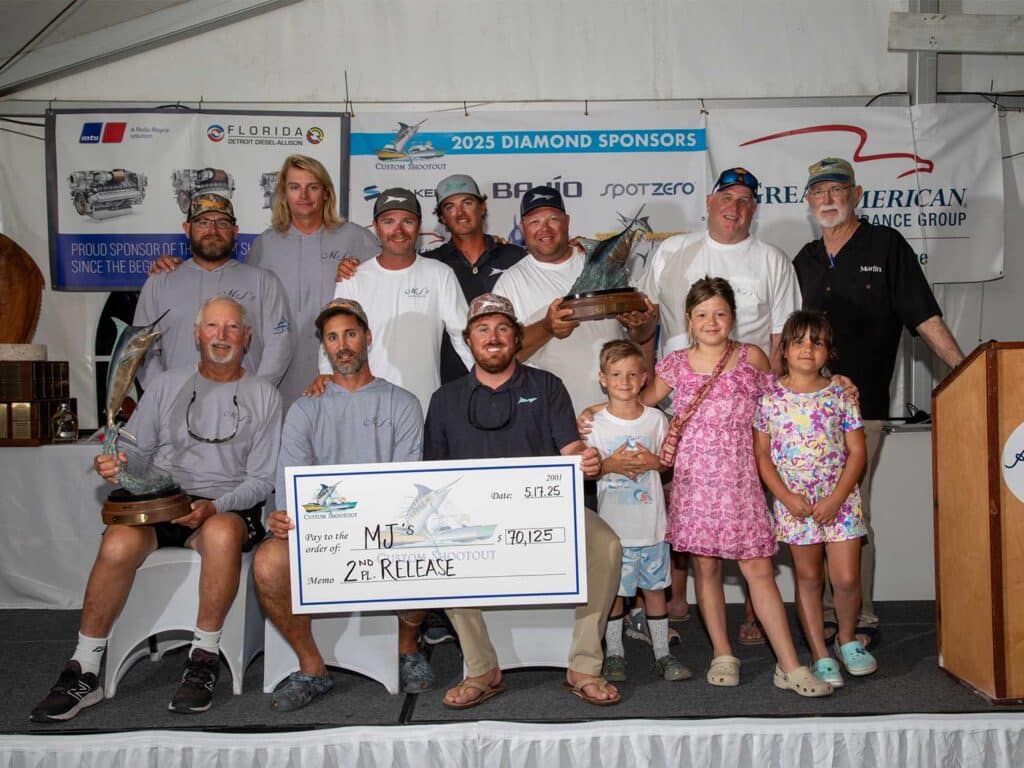 A team of anglers pose in celebration while holding an over-sized check.