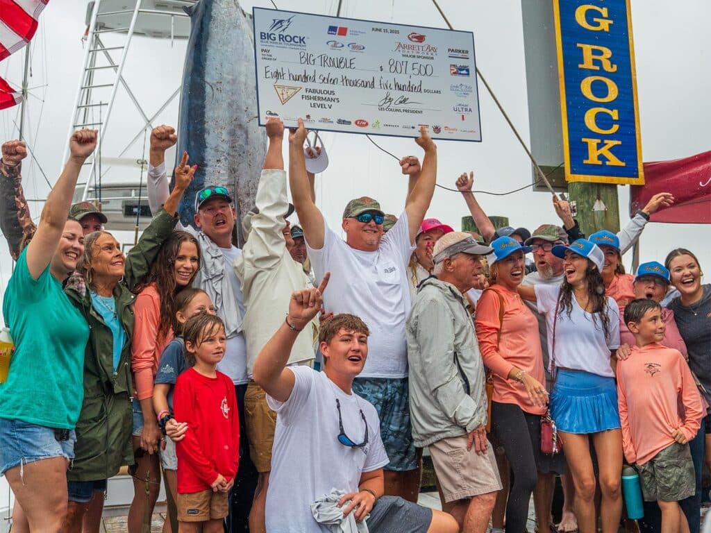 Team Big Trouble stands at the dock of the Big Rock Blue Marlin Tournament beside a weighed marlin.