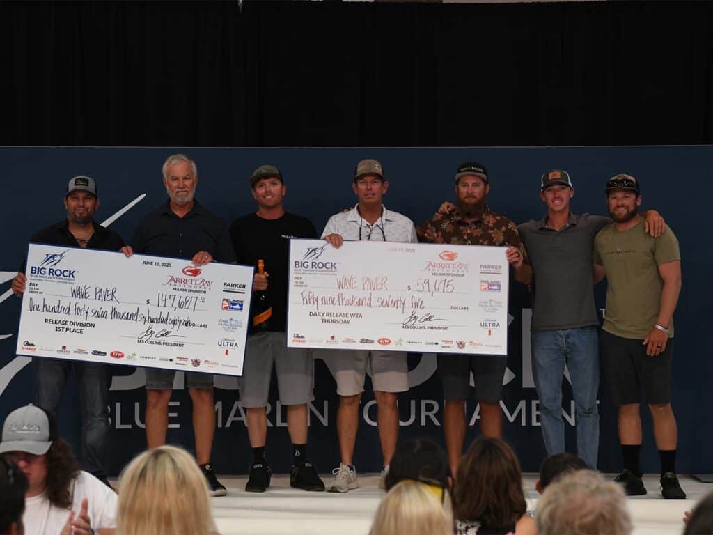 Team Wave Paver stands at the awards ceremony of the 2025 Big Rock Blue Marlin Tournament holding prizes and oversized checks.