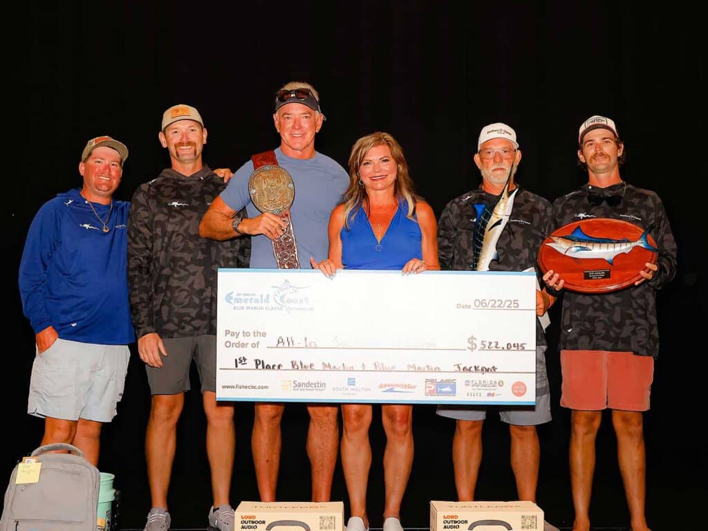 A team of anglers standing on stage holding an oversized check.