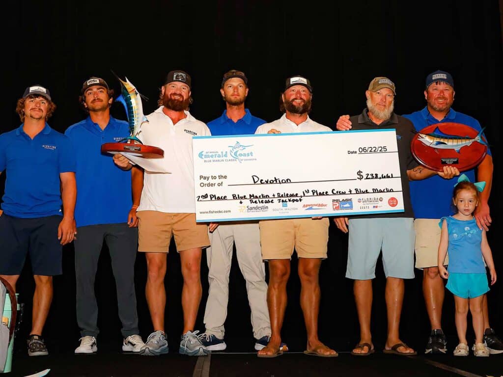 A team of anglers standing on stage holding an oversized check.