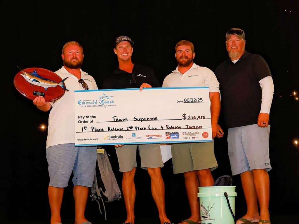 A team of anglers standing on stage holding an oversized check.
