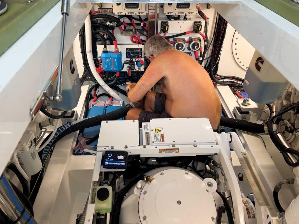 A crew mate performing maintenance on a boat's engine area.