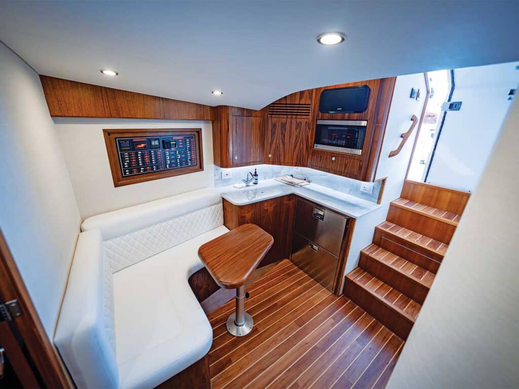 Angled view of the interior salon and galley of the Release 46 Express featuring wood finishes and white cushions and accents.