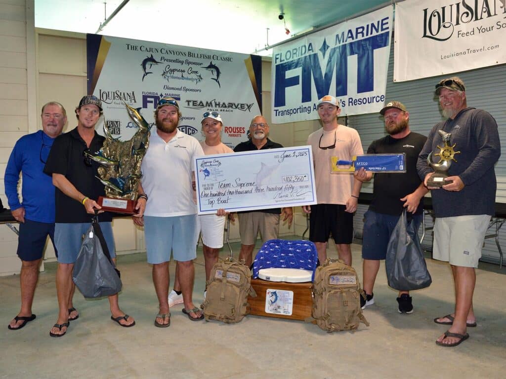 Team Supreme stands at the awards ceremony and holds an oversized check.