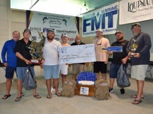Team Supreme stands at the awards ceremony and holds an oversized check.