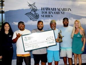 Team Five Star stand in front of a Hawaii Marlin Tournament Series banner and hold their oversized check.