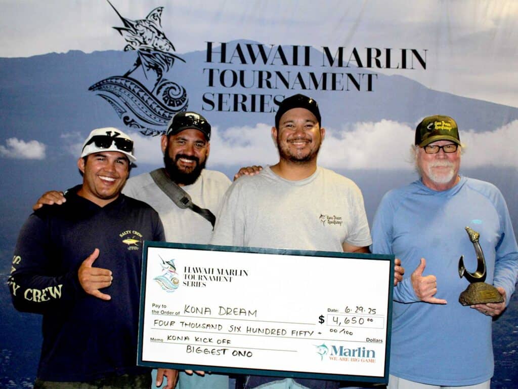 Team Kona Dream stands in front of a Hawaii Marlin Tournames Series banner and hold an oversized check.