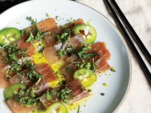 A plate of ahi tuna crudo plated with lime zest and jalapenos.