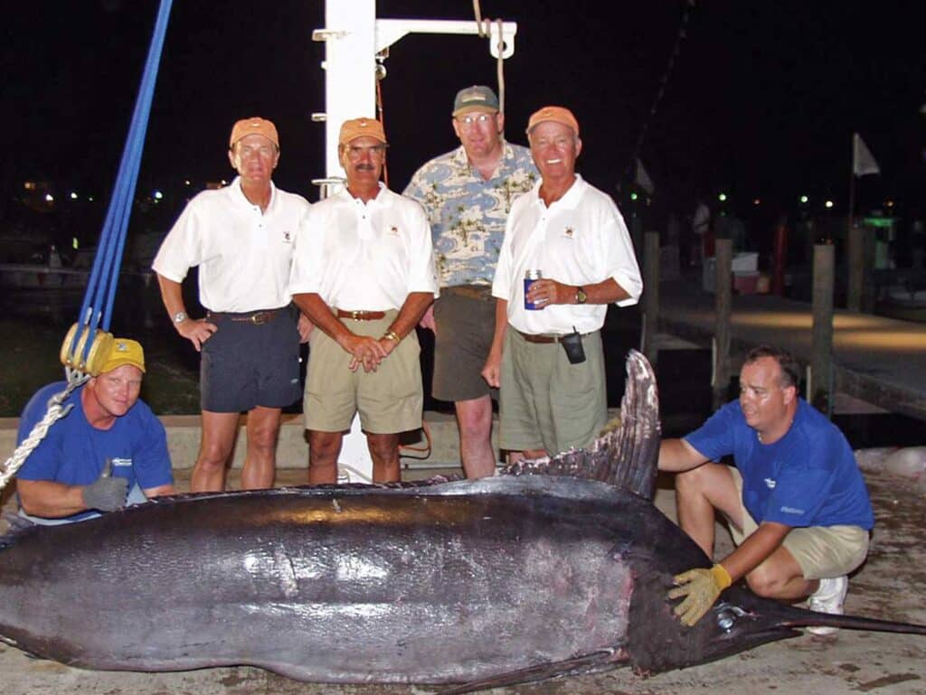 Image of a group of anglers standing behind a weighed blue marlin.