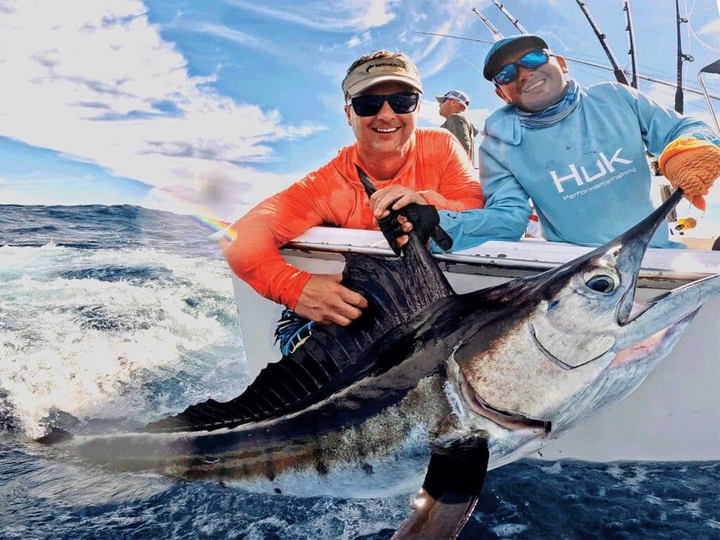 Two men pull a billfish boatside for a photo op