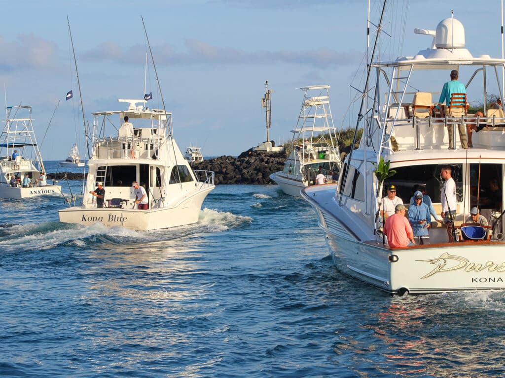 A fleet of sport-fishing boats cruising out of the Kona harbor for a day of fishing.