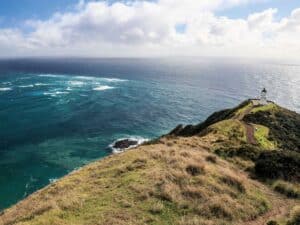 Aerial view of New Zealand's coastline with a lighthouse on the hilltop.