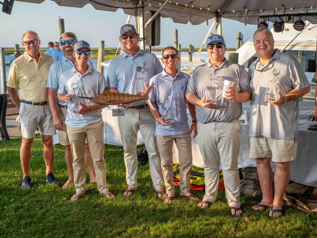 A team of anglers standing underneath a tent on a bright day.