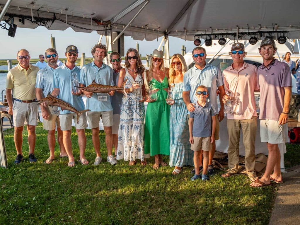 A team of anglers standing underneath a tent on a bright day.