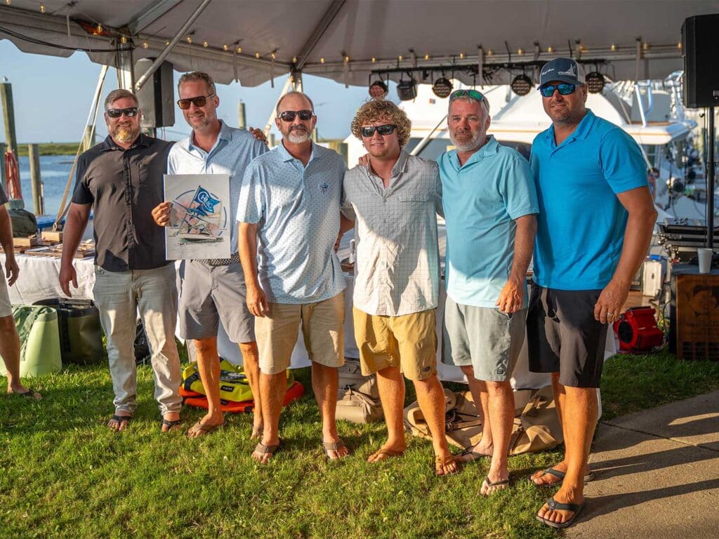 A team of anglers standing underneath a tent on a bright day.