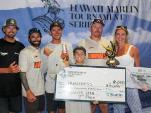 Team Huntress stands in front of an HMTS sign at the awards ceremony and hold up their oversized check.