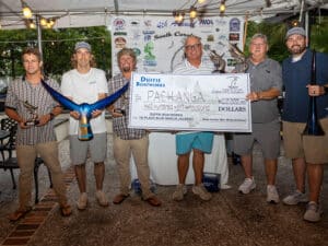 A team of anglers standing at an awards ceremony holding an oversized check.