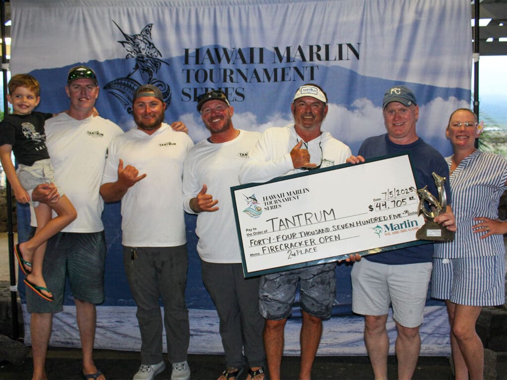 Team Tantrum stands in front of an HMTS sign at the awards ceremony and hold up their oversized check.