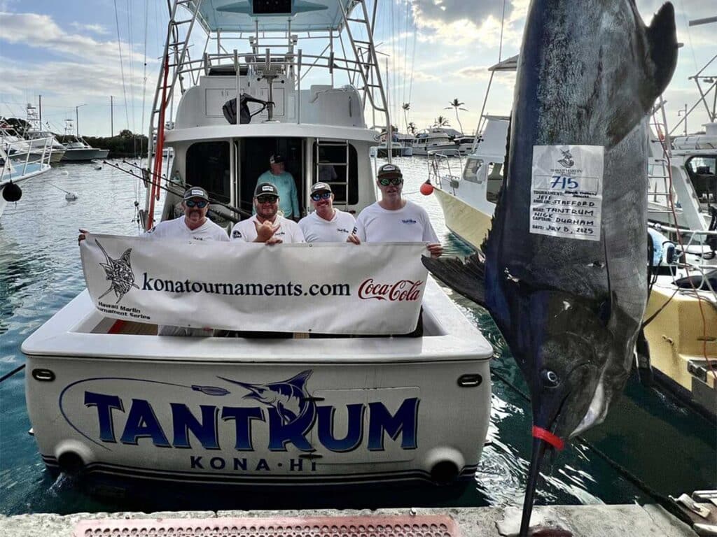 Team Tantrum in the cockpit of their sport-fishing boat next to a large 715-pound blue marlin.