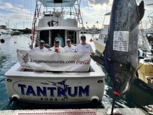 Team Tantrum in the cockpit of their sport-fishing boat next to a large 715-pound blue marlin.