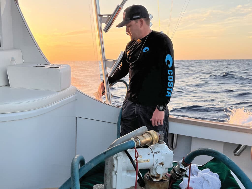 Crewmate transfers fuel into sport-fishing boat tank from an external fuel bladder.