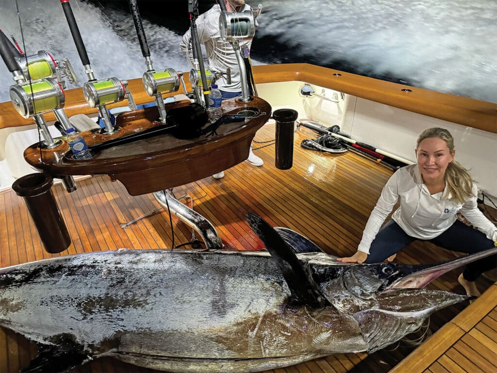 Maria Smith kneels next to an 875-pound blue marlin in the cockpit of Uno Mas.