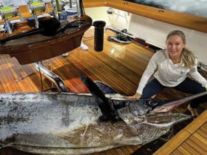 Maria Smith kneels next to an 875-pound blue marlin in the cockpit of Uno Mas.
