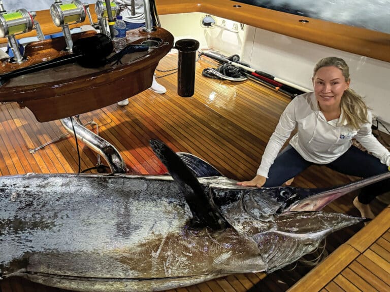 Maria Smith kneels next to an 875-pound blue marlin in the cockpit of Uno Mas.