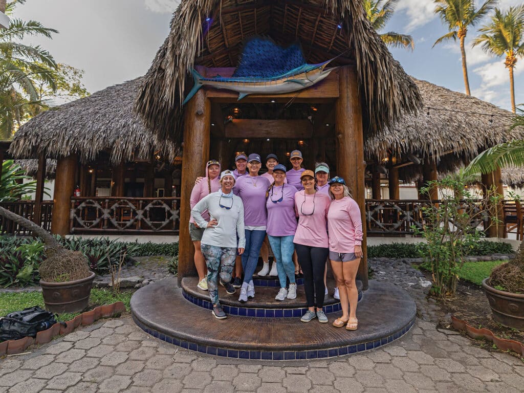 A team of lady anglers standing outside Casa Vieja Lodge's entrance that shows off a large mounted sailfish.