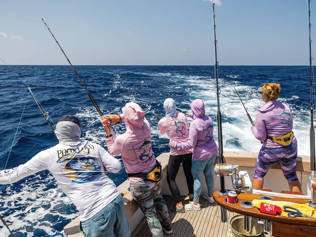 A group of lady anglers practice fishing from the cockpit of a sport-fishing boat.