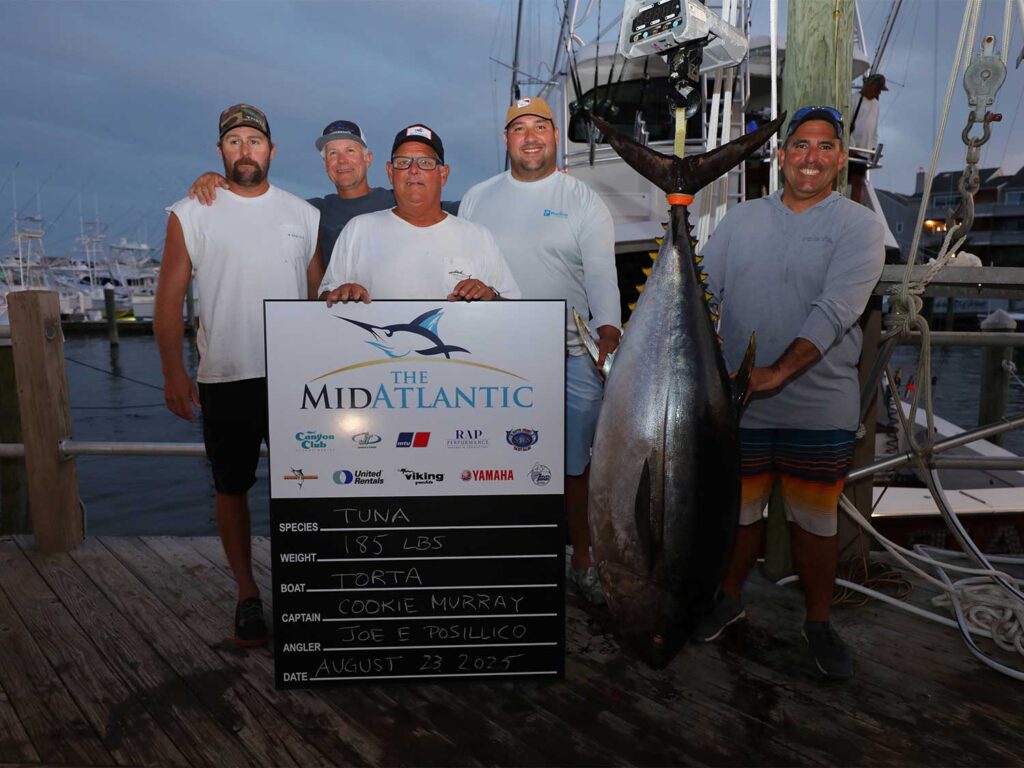 A team of anglers hold up a large bigeye tuna.