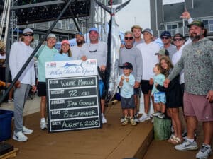 A team of anglers standing next to a white marlin at weigh-in.