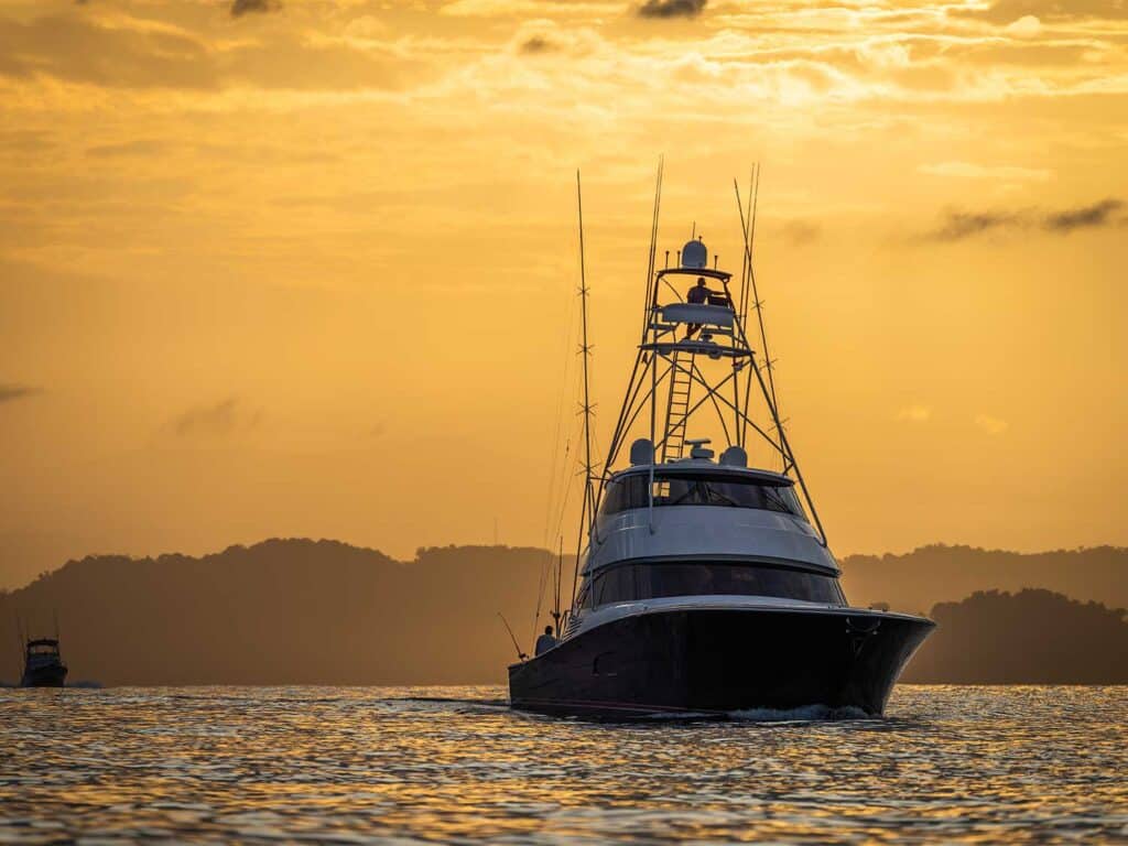 Silhouette of a sport-fishing boat as it cruises across the ocean at susnset.