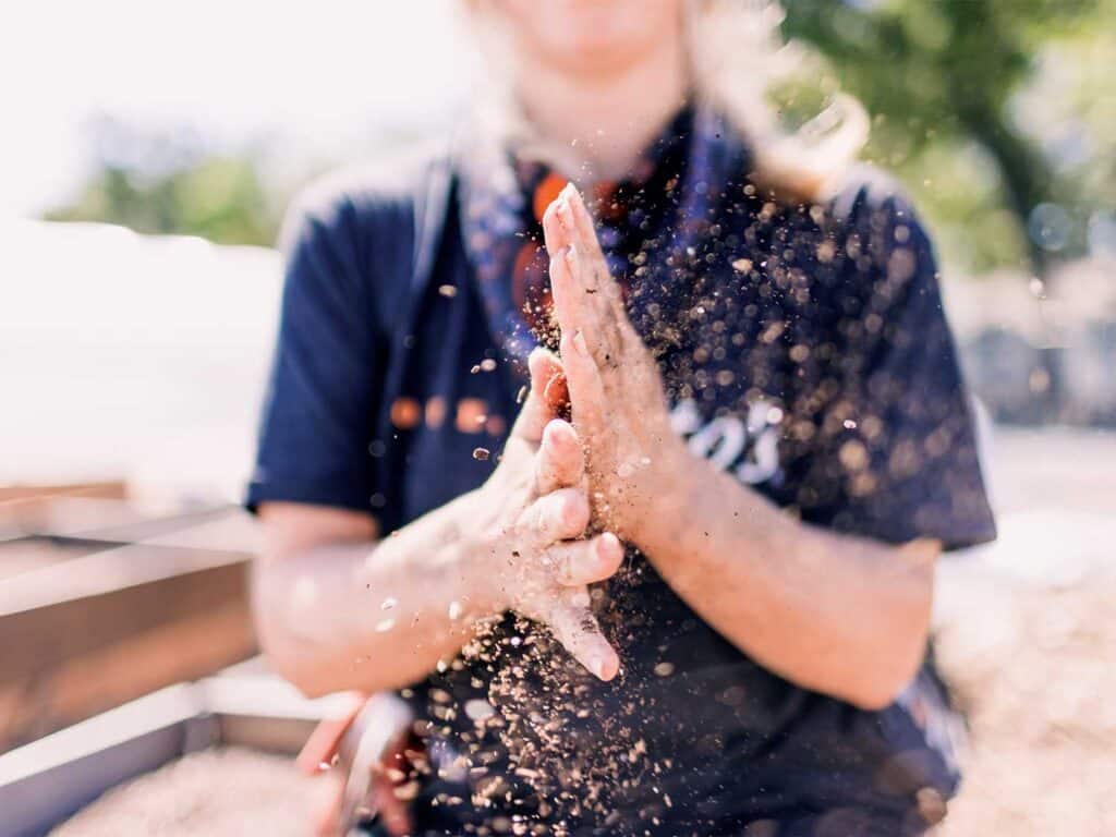 A woman shaking dirt off her hands.