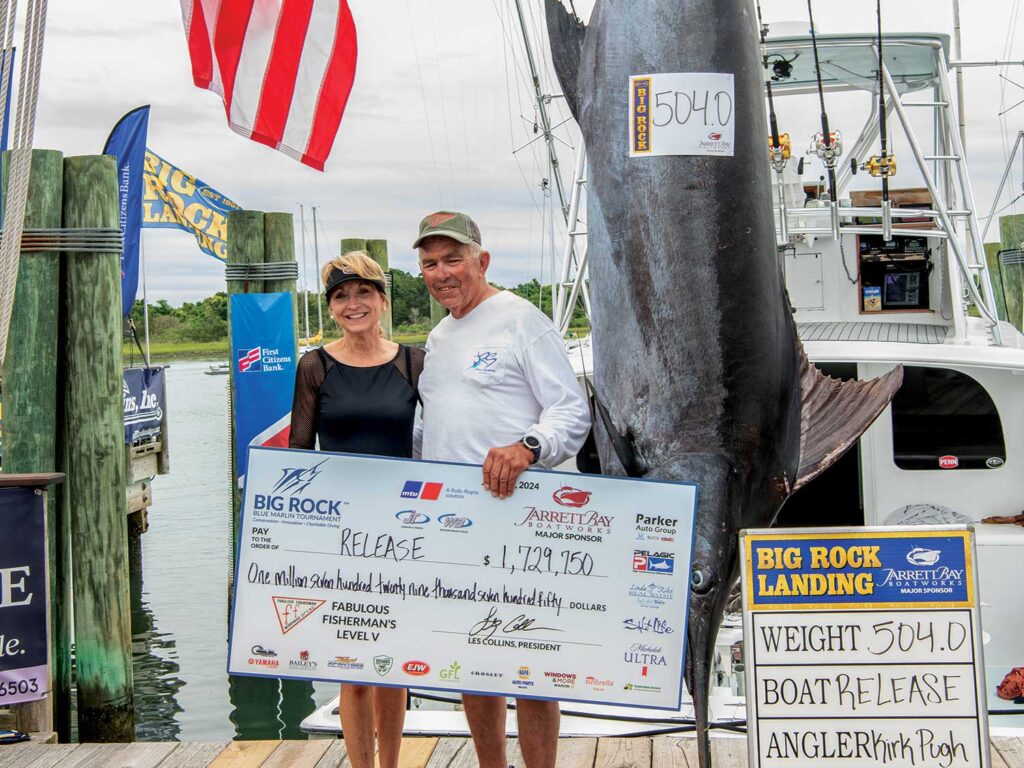 Capt Rom Whitaker next to a large blue marlin being weighed.