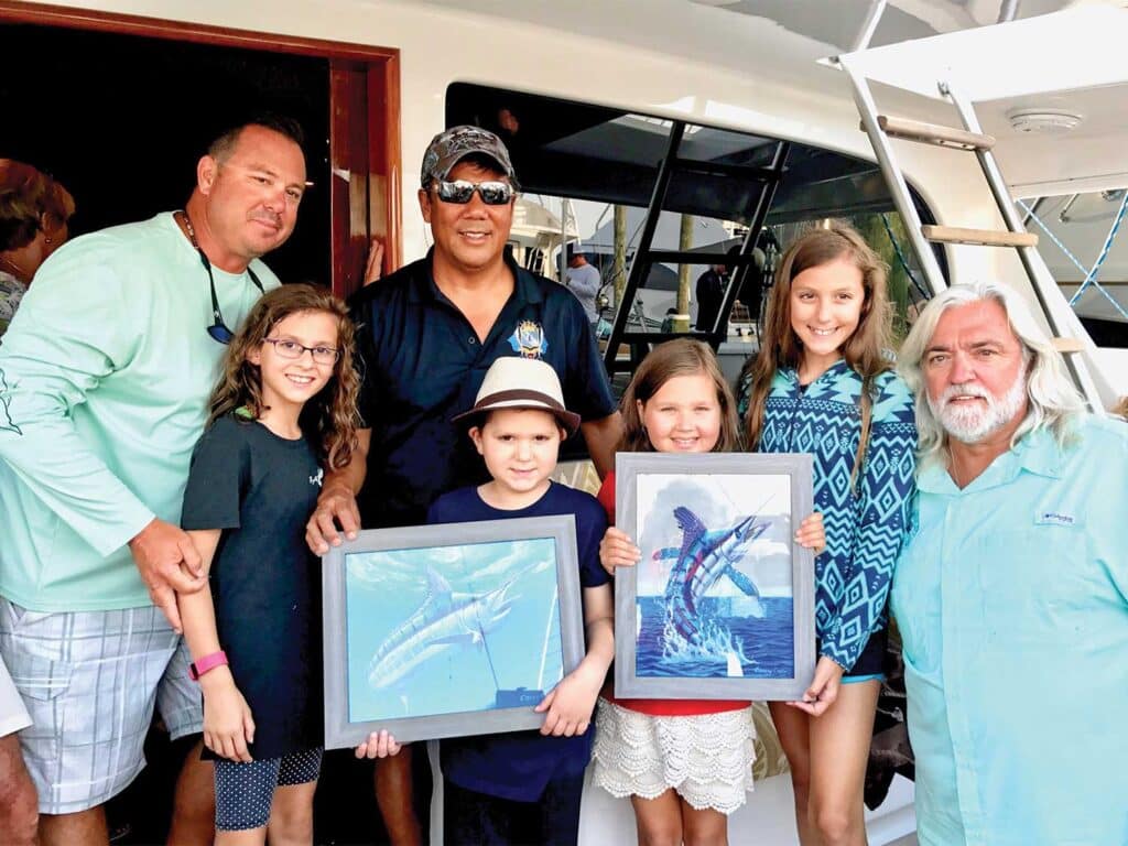 Carey Chen standing with people holding up his artwork.