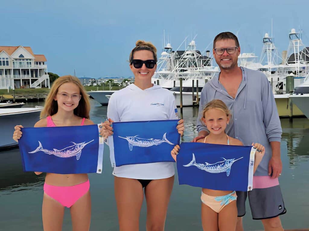Capt. Chris Kubik, his wife, and two daughters pose with white marlin release flags.