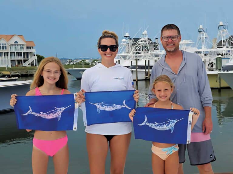 Capt. Chris Kubik, his wife, and two daughters pose with white marlin release flags.