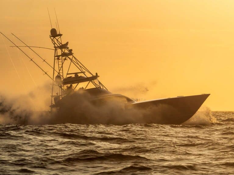 A sport-fishing boat cruising across the ocean with golden hour on horizon.